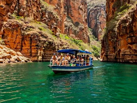 Barco de passeio entre as paredes de pedra avermelhada do Cânion do Xingó, na água verde do Rio São Francisco